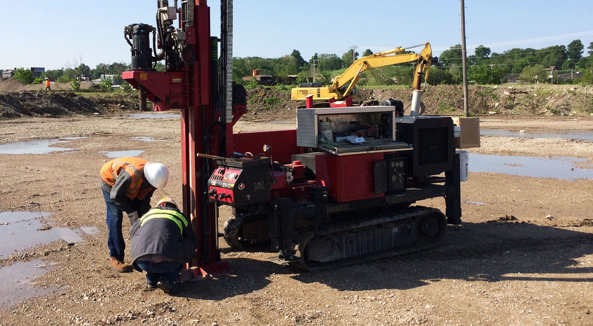 Two workers and machinery doing site assessment at former Carrie Ave. Rail Yard.